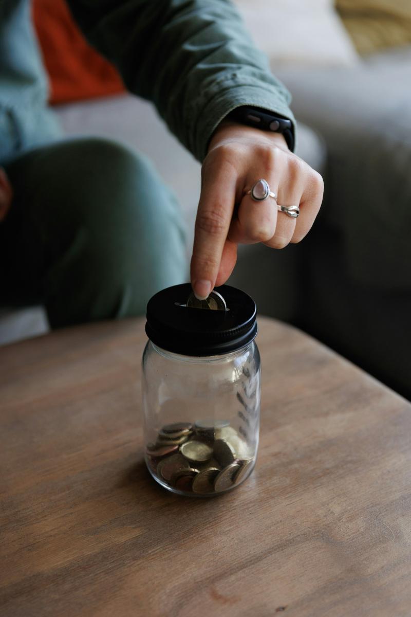 person putting money in jar