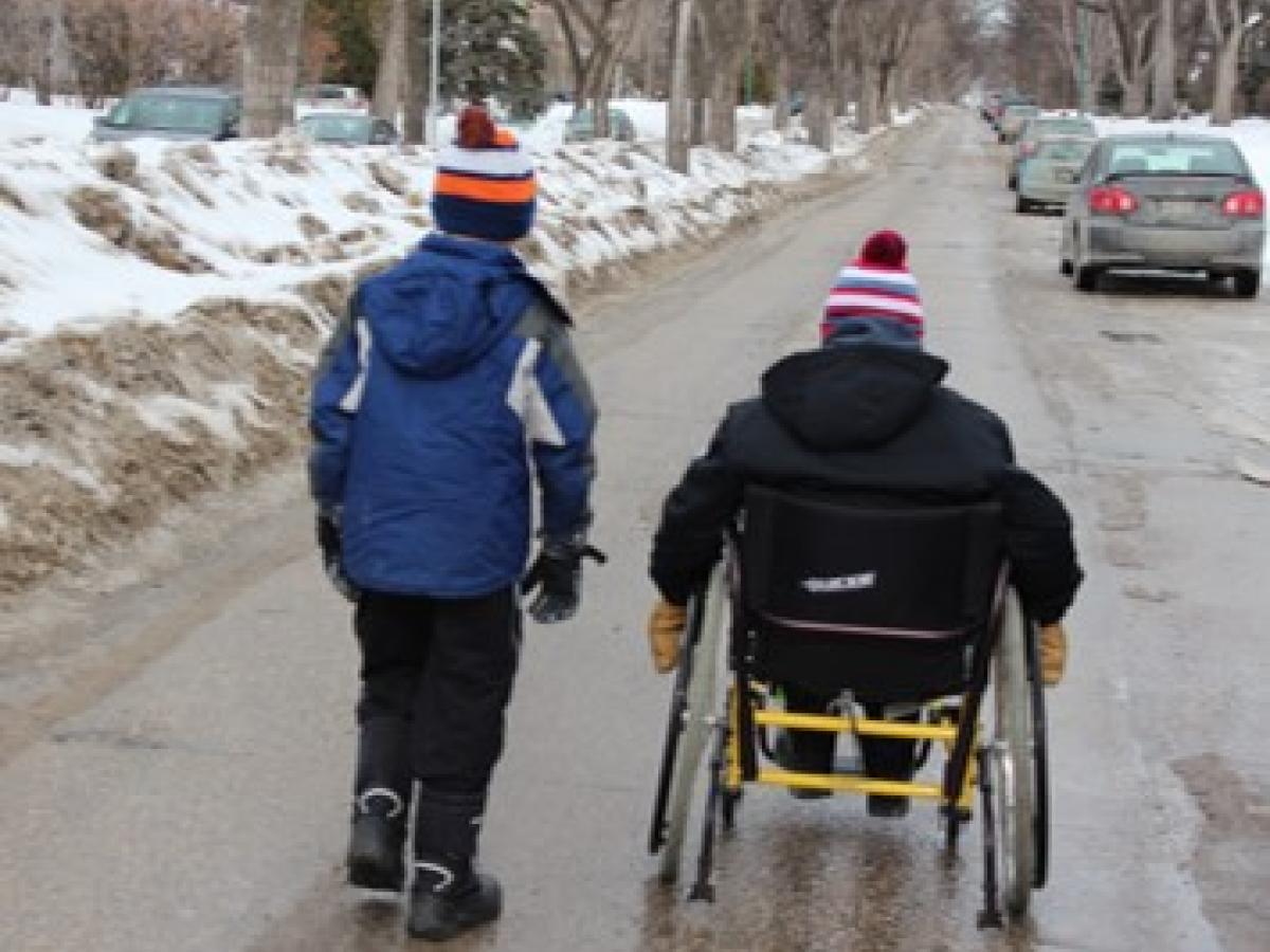 young boys wheeling down snowy street