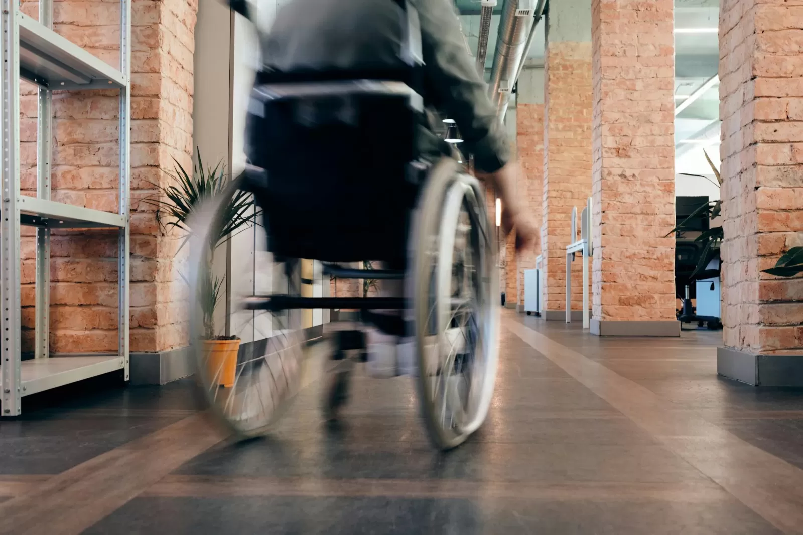 manual wheelchair user pushing chair in indoor brick hall 